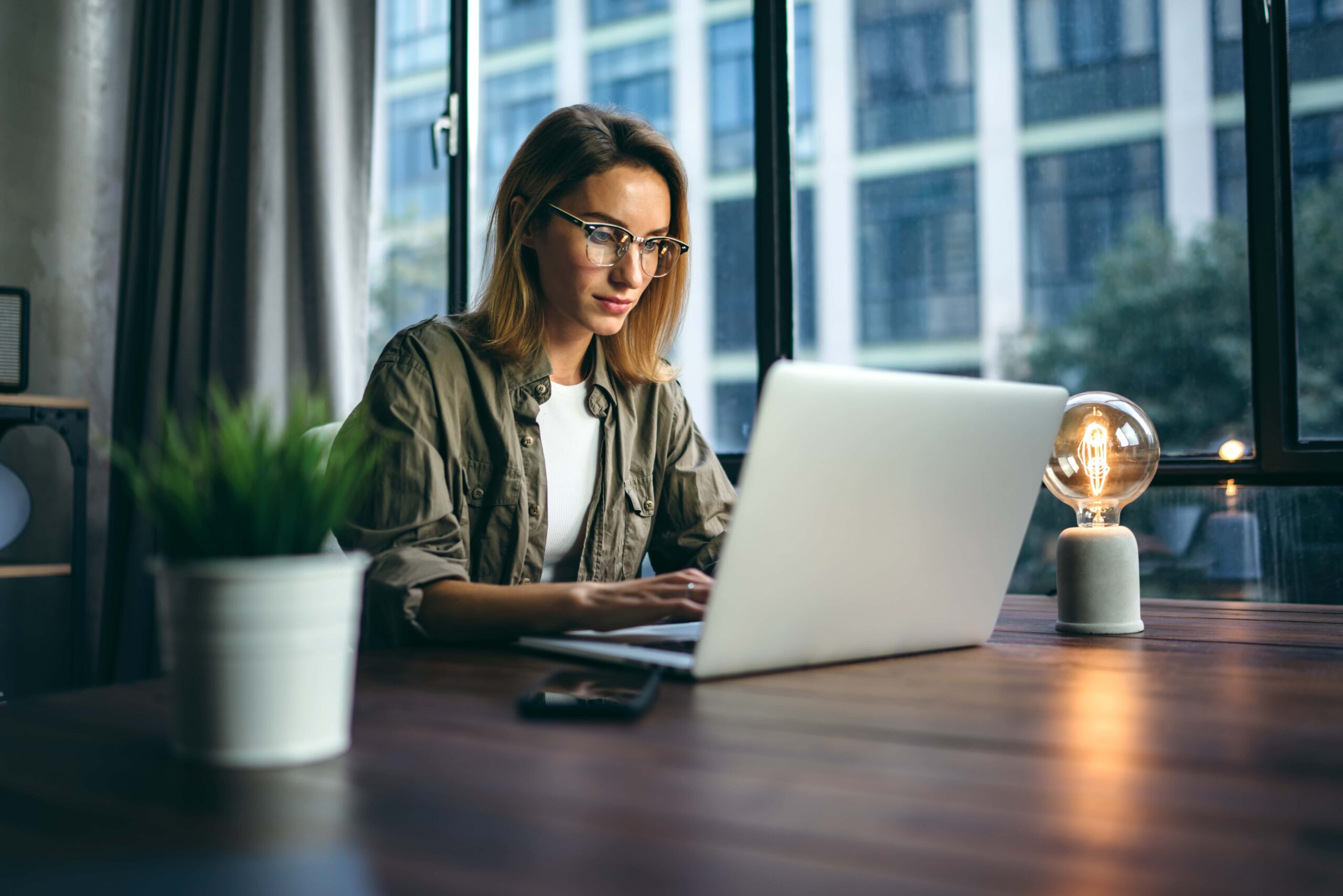 Young woman working with a laptop. Female freelancer connecting to internet via computer. Businesswoman at work scaled