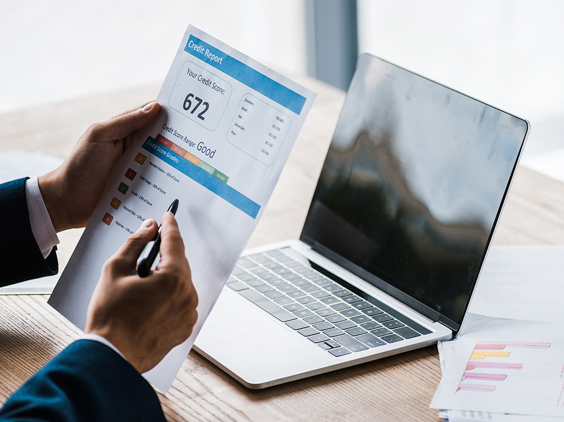 man holding paper with credit report letters near laptop with blank screen